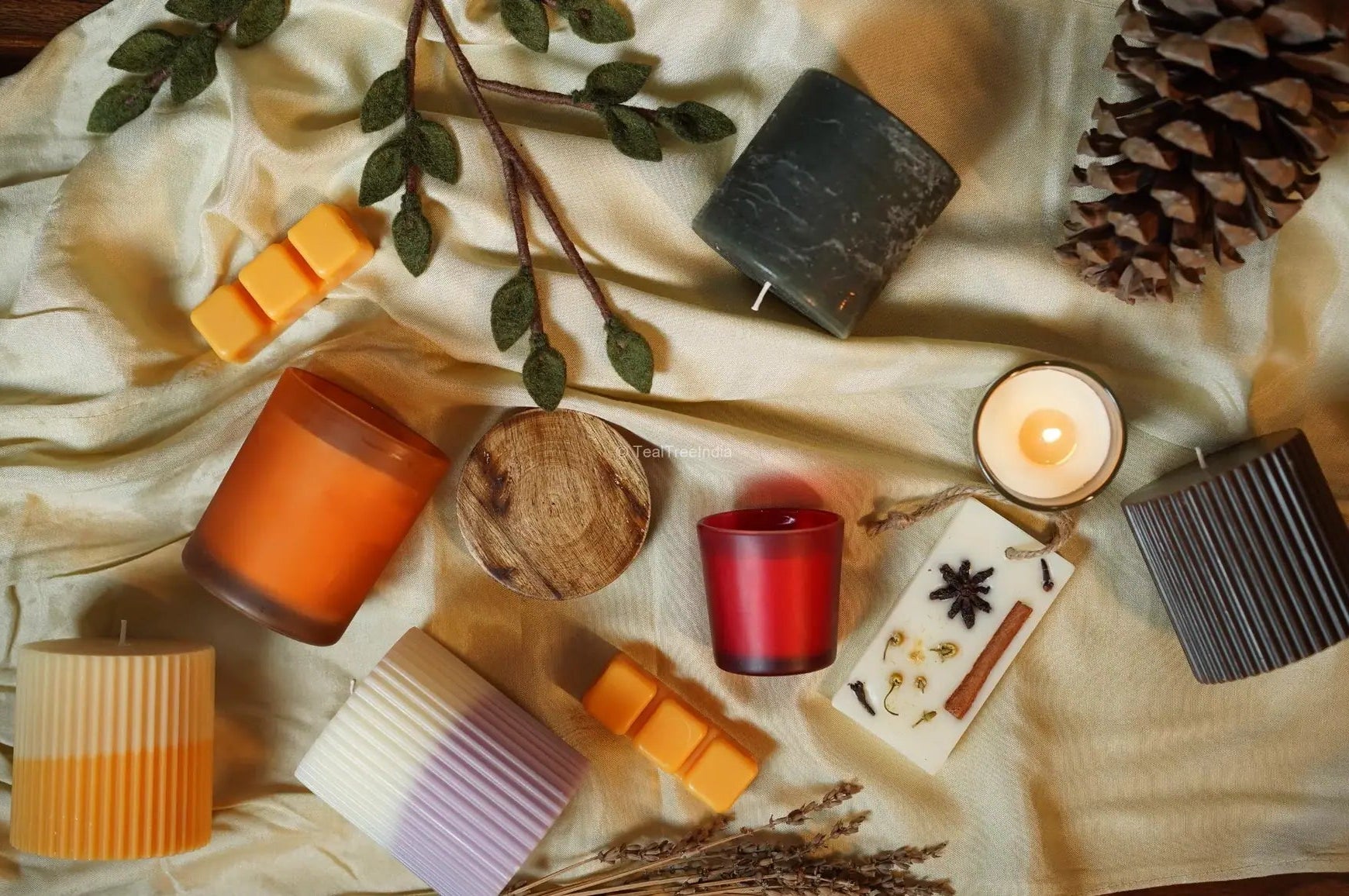 Flatlay of artisan pillar candles, wax melts, and botanical sachets styled on fabric – perfect for home decor and gifting.