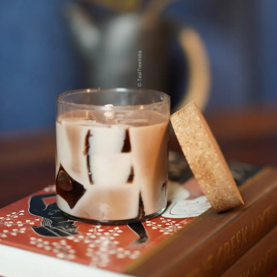 Hand-poured soy wax candle with embedded chunky wax pieces in a clear glass jar, placed on a book.
